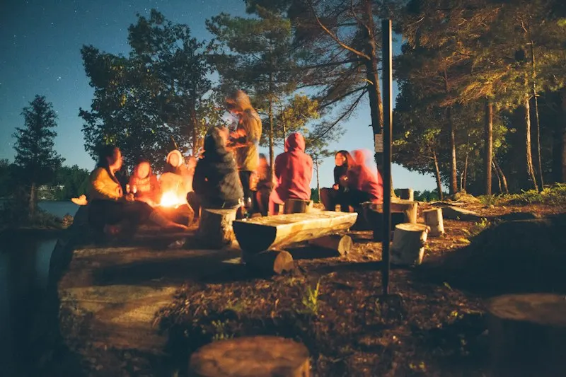 People gathered around a campfire at a forest campsite