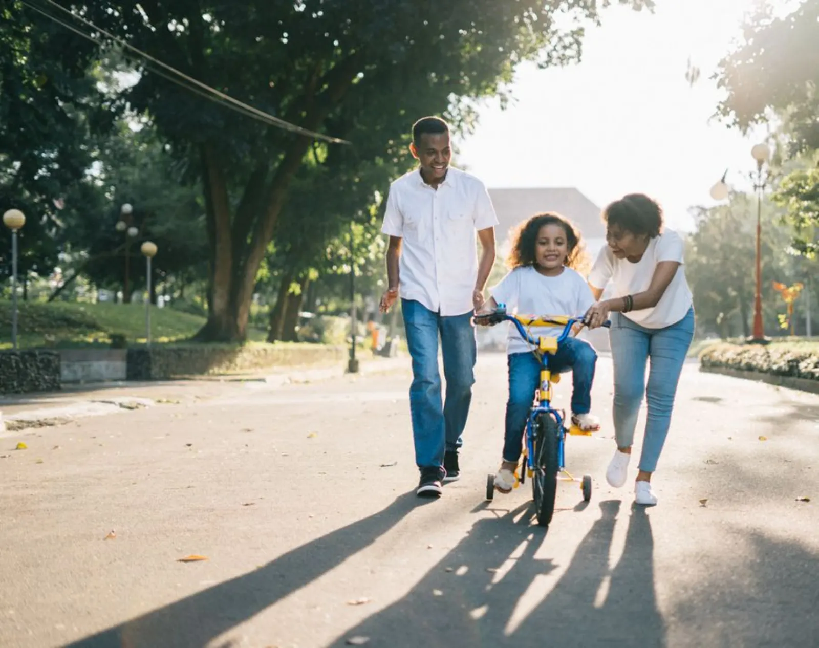 Parents helping a child ride a bike outdoors